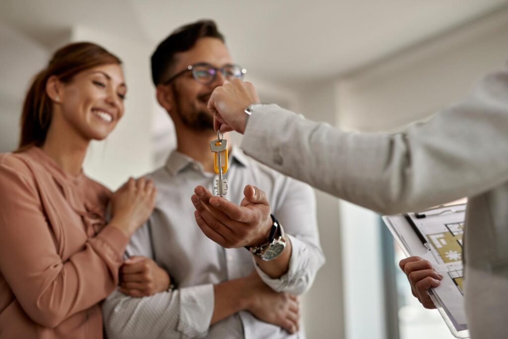 Com alta de 5,1%, Moema lidera valorização imobiliária em São Paulo Casal sorridente recebe as chaves de um imóvel das mãos de um corretor